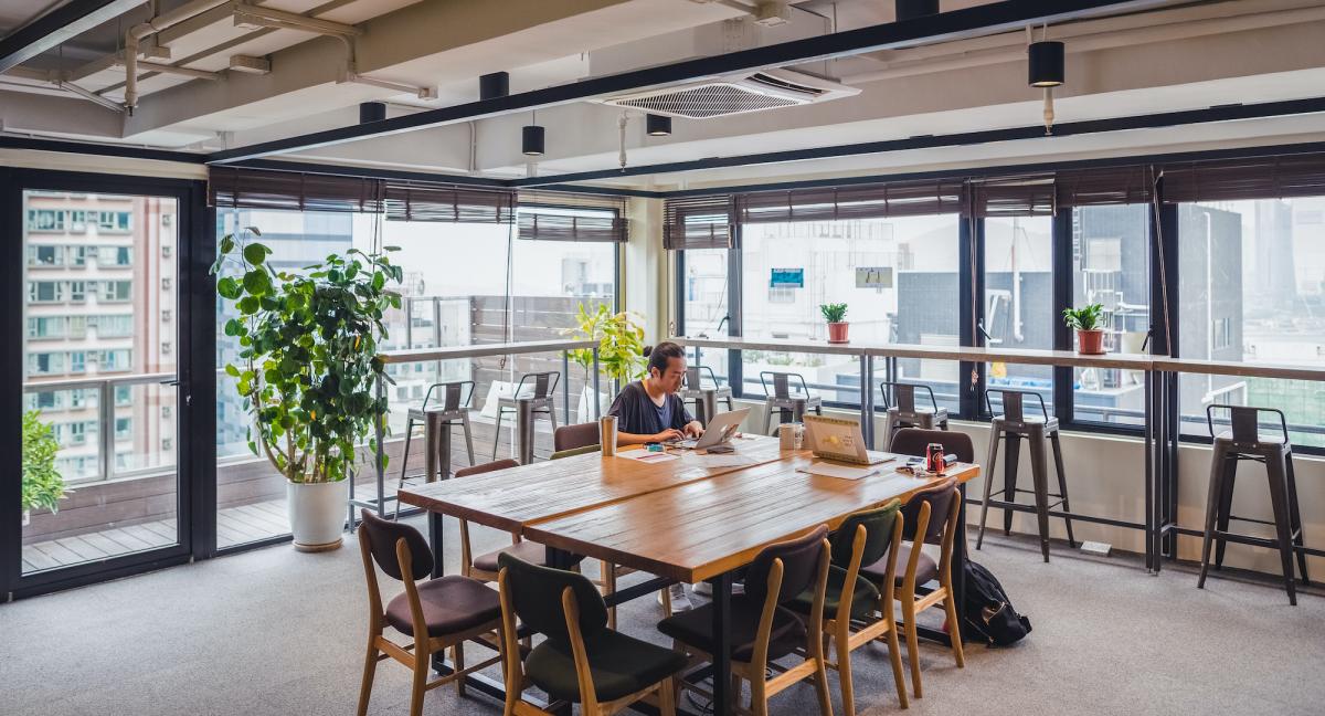 Man working at the coworking space in Garage Society Sheung Wan, with a rooftop view overlooking the city